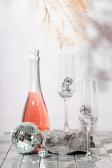  New Year's champagne and disco balls on the table. Modern Christmas and New Year's vertical card