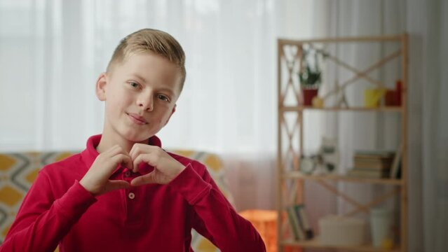 Blond schoolboy sends air kiss and makes heart gesture