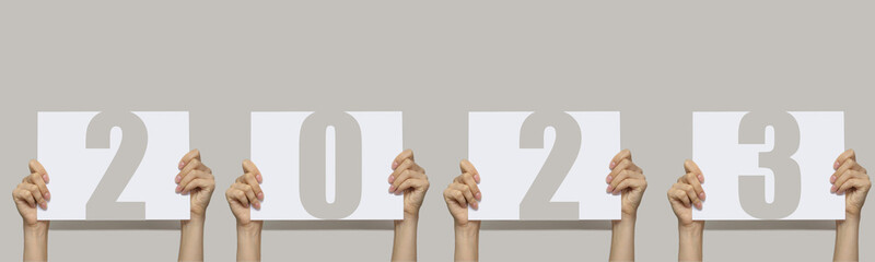 new year 2023. Women's hands hold signs with numbers two thousand twenty-third. Concept of welcome...