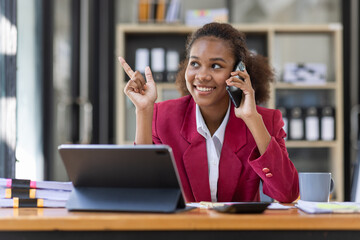 Young businesswoman cheerful african american lady working at workplace office, workdesk with laptop financial documents having phone conversation, copy space