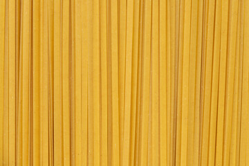 Durum fettuccine noodles background. Close up of raw spaghetti. Full frame of pasta
