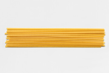 Uncooked durum fettuccine pasta isolated on white background. Raw spaghetti or noodles - obrazy, fototapety, plakaty