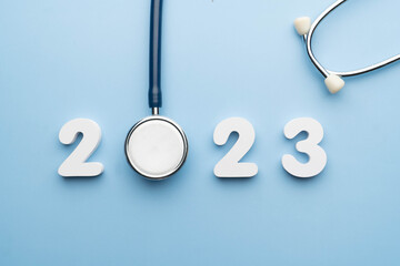 Stethoscope with 2023 number on blue background. Happy New Year for health care and medical banner...