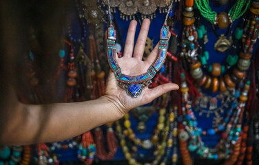 Hand of a female tourist holding a Moroccan costume jewelry pendant in a store in Marrakech in...