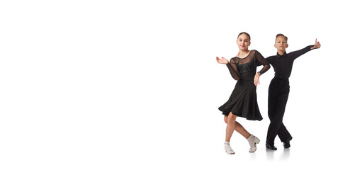 Two kids, school age girl and boy in black stage costumes dancing ballroom dance isolated on white...