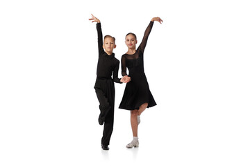 Two kids, school age girl and boy in black stage costumes dancing ballroom dance isolated on white...