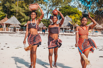 Women with typical kenyan clothes stroll on the beach