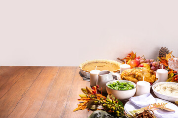 Thanksgiving family party dinner table setting with plates, cutlery, glasses, traditional dishes - baked turkey or chicken, pumpkin pie, fruits, mashed potatoes, green beans, wooden background