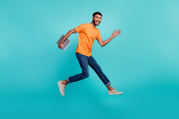 Fototapeta na wymiar Full size profile photo of excited active man jump rush fast hold netbook isolated on aquamarine color background