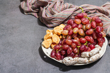 Snack plate with cheese, grapes and dried sausages. Charcuterie antipasto, stone concrete background