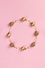 Circle frame of golden Christmas balls and glitter confetti hearts on pink background