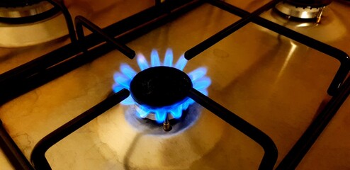 Close-up of blue fire over the home kitchen stove. Gas stove with flames burning propane gas....