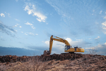backhoe on mound of dirt big sky space for text