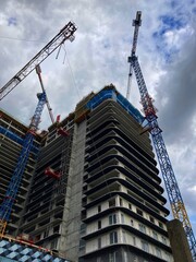 Construction site with construction crane building in the city center new sky scrapers with blue windows in sunny day with blue sky. Building site tower, construction skyscraper