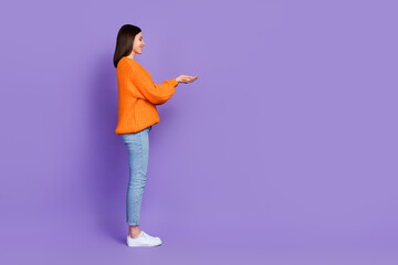Full body profile portrait of positive person hands hold empty space isolated on purple color background