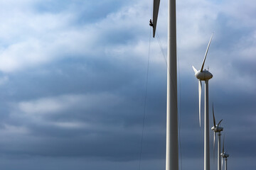 Man working on a wind turbine against blue sky