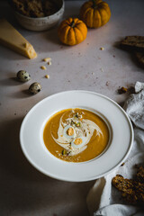 Homemade pumpkin cream soup with quail eggs, parmesan , sour cream and pistachios and biscotti with dried tomatoes and pistachios on white background 