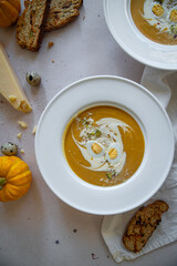 Homemade pumpkin cream soup with quail eggs, parmesan , sour cream and pistachios and biscotti with dried tomatoes and pistachios on white background 