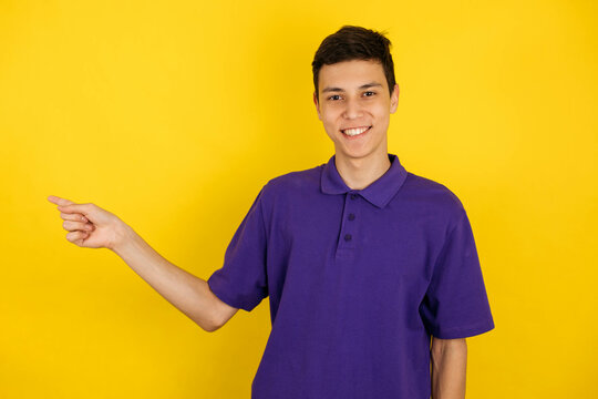 Portrait of a young boy in a very pery T-shirt on a blue background, points a finger to the side