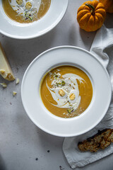 Homemade pumpkin cream soup with quail eggs, parmesan , sour cream and pistachios and biscotti with dried tomatoes and pistachios on white background 