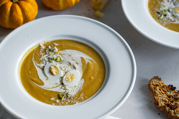Homemade pumpkin cream soup with quail eggs, parmesan , sour cream and pistachios and biscotti with dried tomatoes and pistachios on white background 