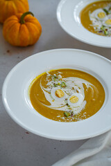 Homemade pumpkin cream soup with quail eggs, parmesan , sour cream and pistachios on white background 
