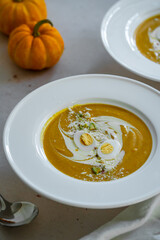 Homemade pumpkin cream soup with quail eggs, parmesan , sour cream and pistachios on white background 