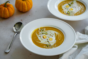Homemade pumpkin cream soup with quail eggs, parmesan , sour cream and pistachios on white background 