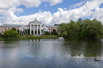 Building, pond, floating house for ducks and ducks. Botanical park in Moscow. Summer day cloudy sky.