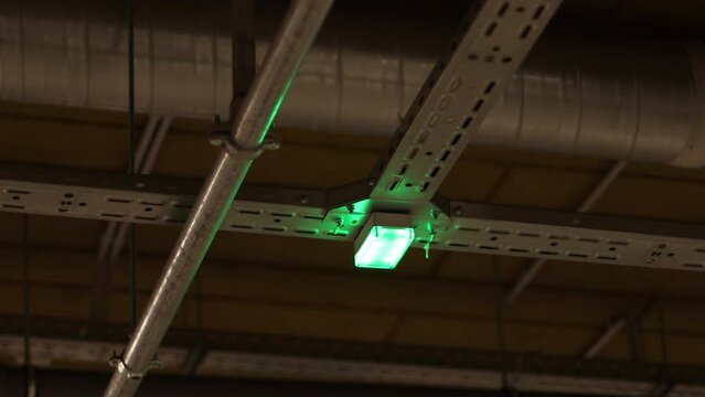 Single Flashing Green Light on a Free Parking Place in the Mall. City Shopping Mall Parking Lot Automated Parking Spot Occupation Ceiling Sensor Indicator.
