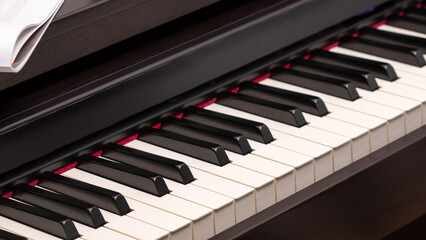 Naklejka premium Music composition with piano keyboard. Electronic piano with sheet music. Piano lesson. Music education. Selective focus