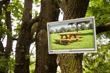Picnic area concept with sign indicating in the countryside and wooden picnic table on a green...