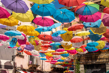 beautiful street in the center of Catania with many colorful umbrellas hanging over the street