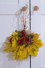 Autumn colorful leaves bouquet hang on white door