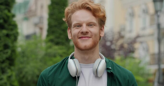 Portrait of red haired man standing in park and looking at the camera