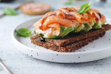 A rye bread sandwich with avocado and salmon