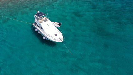 Aerial drone top view photo of small yacht - boat anchored in tropical exotic paradise bay with emerald open ocean