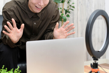 ノートパソコンで動画配信をする若い男性
