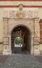 Germany, Wismar - July 13, 2022: Monumental sculpted beige-stone entrance gate to Furstenhof, a renaissance princely court, palace, set in front front facade featuring humans and dragons