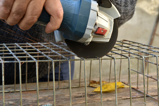 The picture shows the hands of the master in which he holds the grinder tool and cuts its metal mesh.