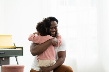 Happy father hugging little daughter at home. Happy African American father embracing daughter