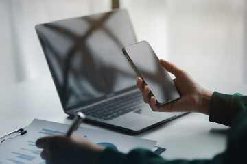 Business man looking at financial information from a mobile phone, he is checking company financial...