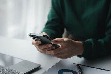Business man looking at financial information from a mobile phone, he is checking company financial documents, he is an executive of a startup company. Concept of financial management.