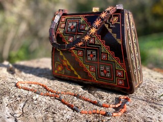 A women's bag made of wood with an ancient folk Western Ukrainian ornament and a coral necklace