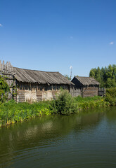 Fototapeta na wymiar Suzdal, Vladimir region, Russia -august, 18, 2022: the ancient Shchurovskoye settlement with medieval wooden buildings among the bright green foliage of trees and blue clear sky on a sunny summer day