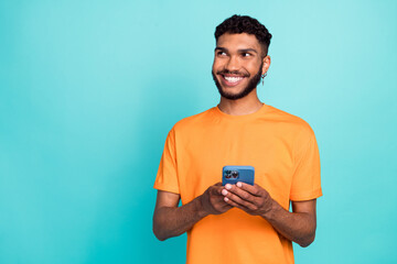 Photo of cute dreamy guy wear orange t-shirt typing facebook telegram modern gadget empty space...