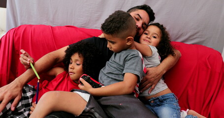 Hispanic father with children at home sofa, real life south american people