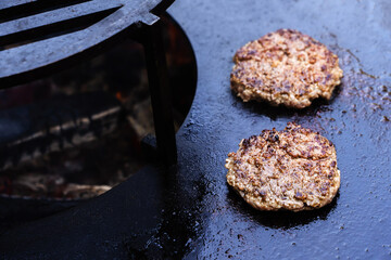 Cooking cutlets on an industrial grill. The process of roasting meat products on fire and coals. Close-up