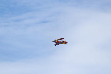 Little red biplane flying across semi cloudy sky. This plane almost reminded me of the red baron. It has such an old look to it. I took this picture while standing on the beach in Cape May New Jersey.