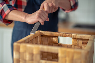 Carpenter cutting off the excess glue from the box edging